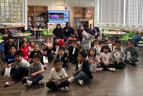 Class sitting on the floor holding dental goodie bags