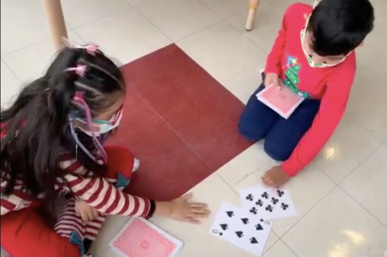 Two students sitting on the floor playing the card game War