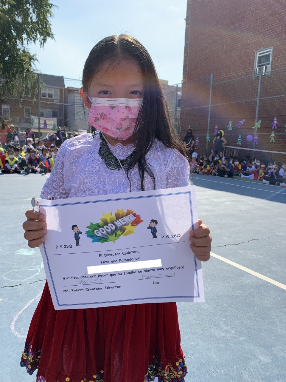 Nathaly holds up her Good News Call certificate in the schoolyard