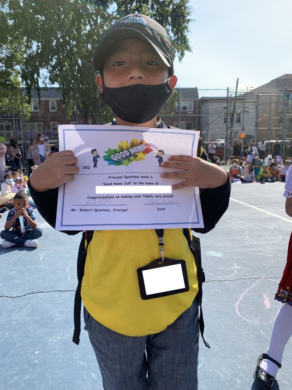 Erick holds up his Good News Call certificate in the schoolyard