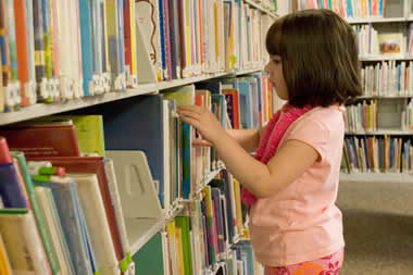 Girl choosing a book from a library shelf