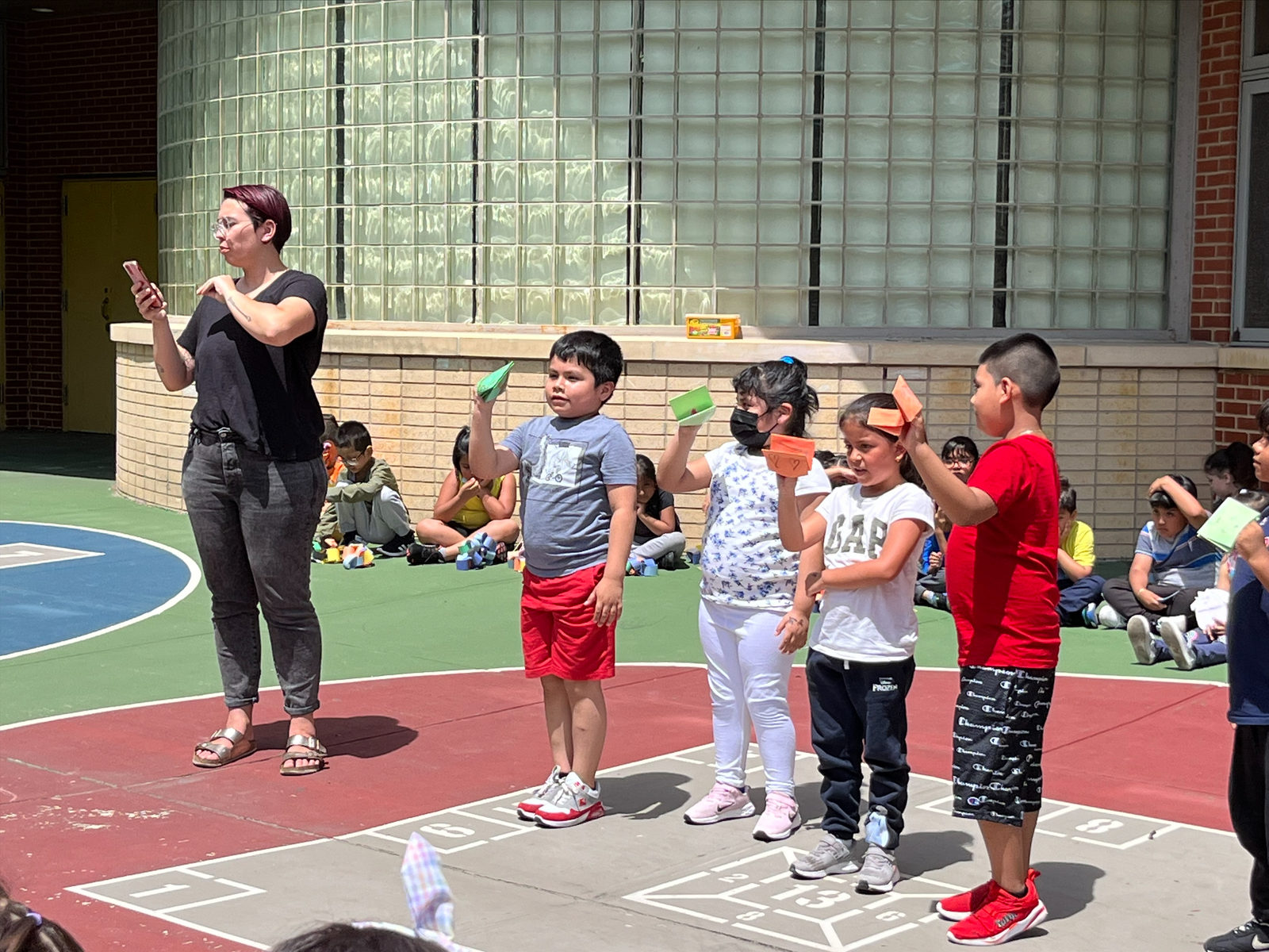 A group of students raise their puppets during a schoolyard performance