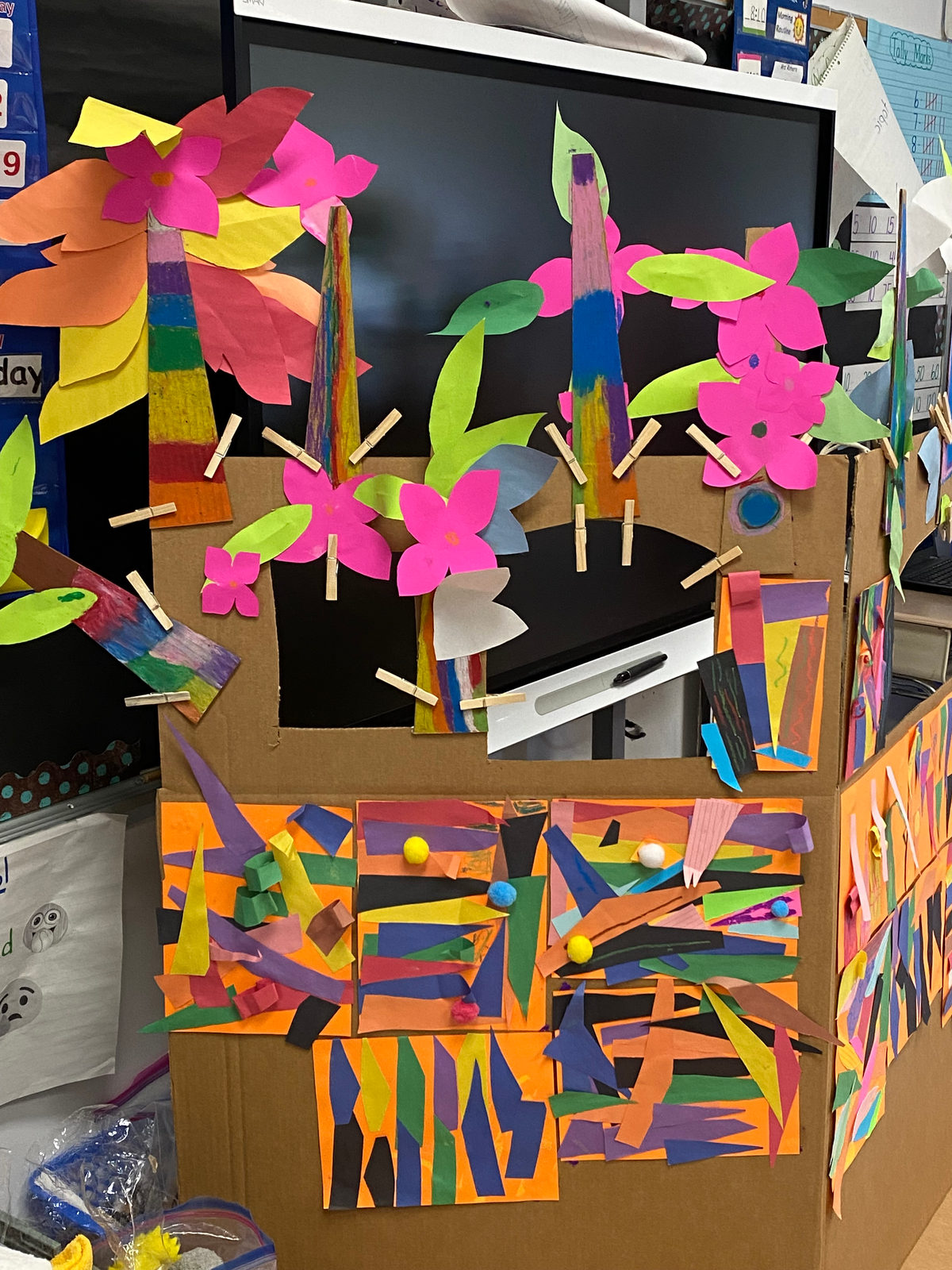 Paper flowers and leaves crown the top of the class puppet stage