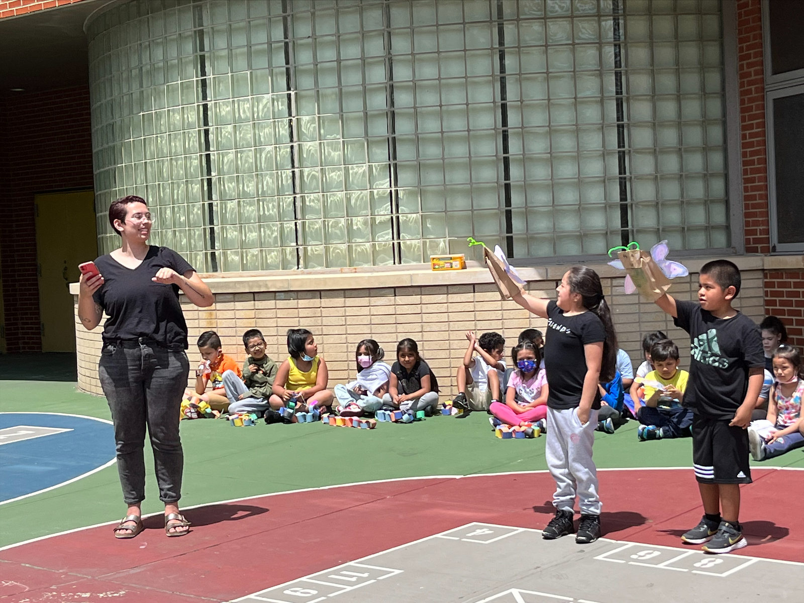 A Puppetry in Practice teaching artist leads students in a movement warm-up in the schoolyard