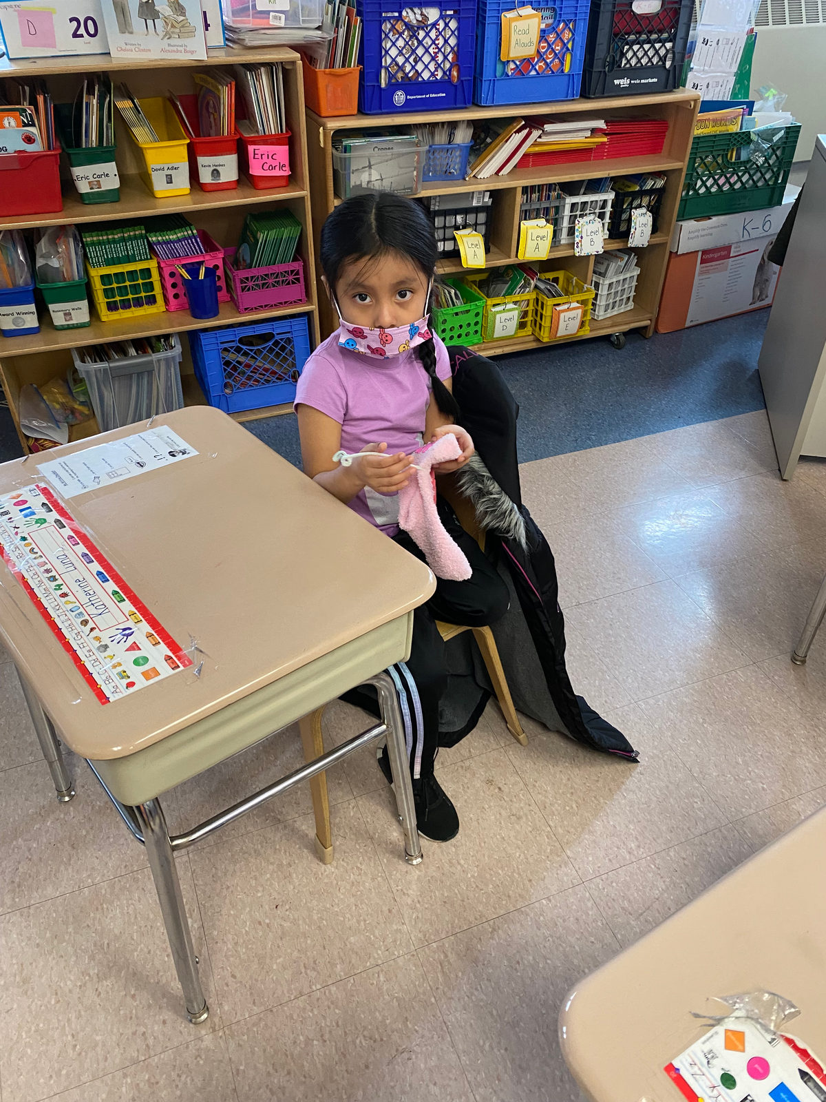 A student sits at her desk with the puppet she designed