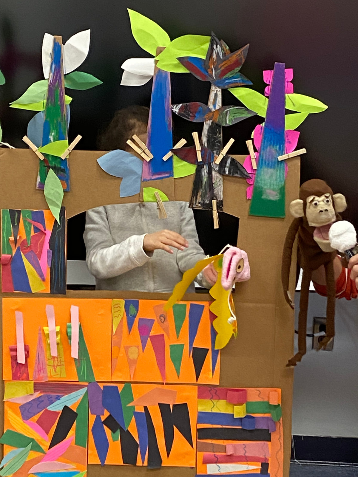 A monkey puppet and other puppets perform from the class puppet stage