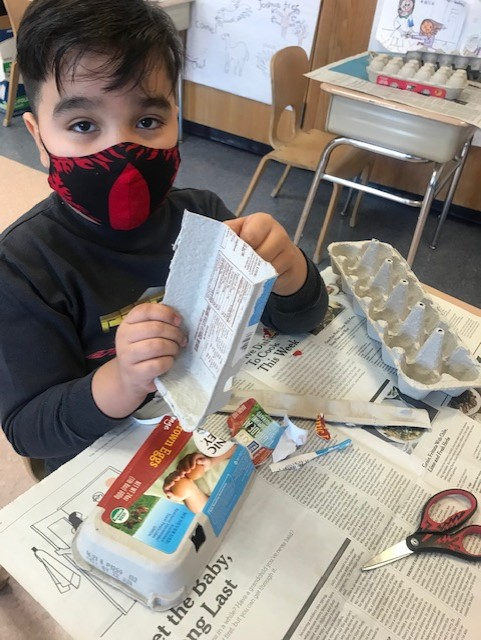 Student cutting up a recycled egg carton