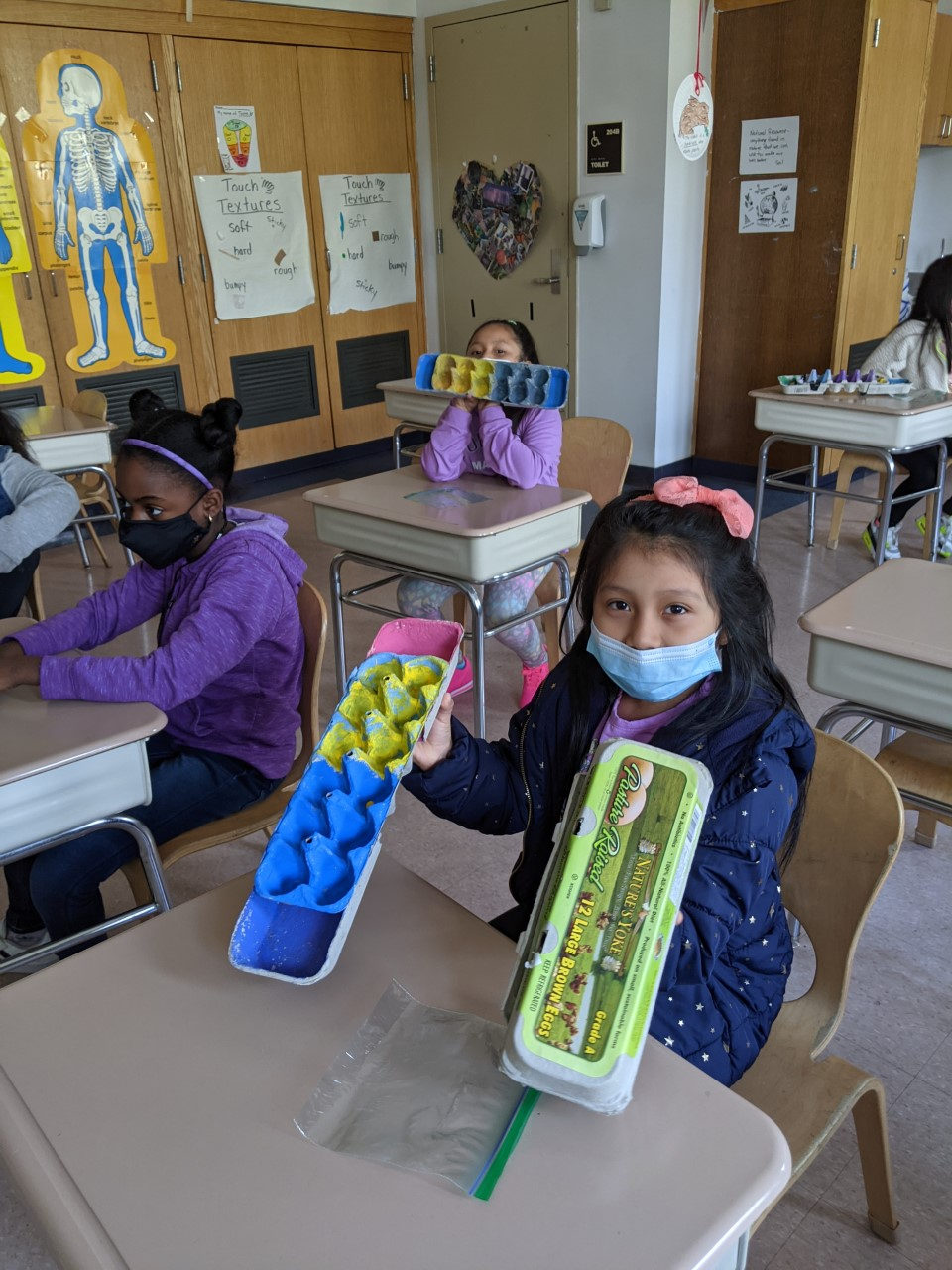 Students showing their painted egg-carton Mancala boards