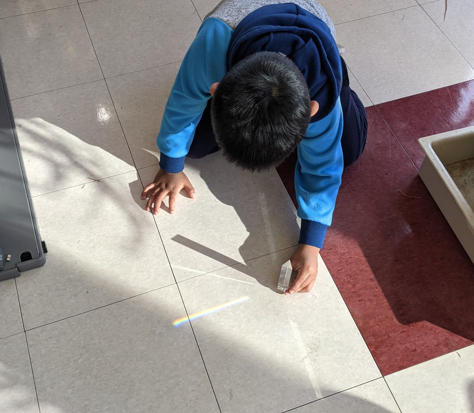 Student making a rainbow on the floor with a prism