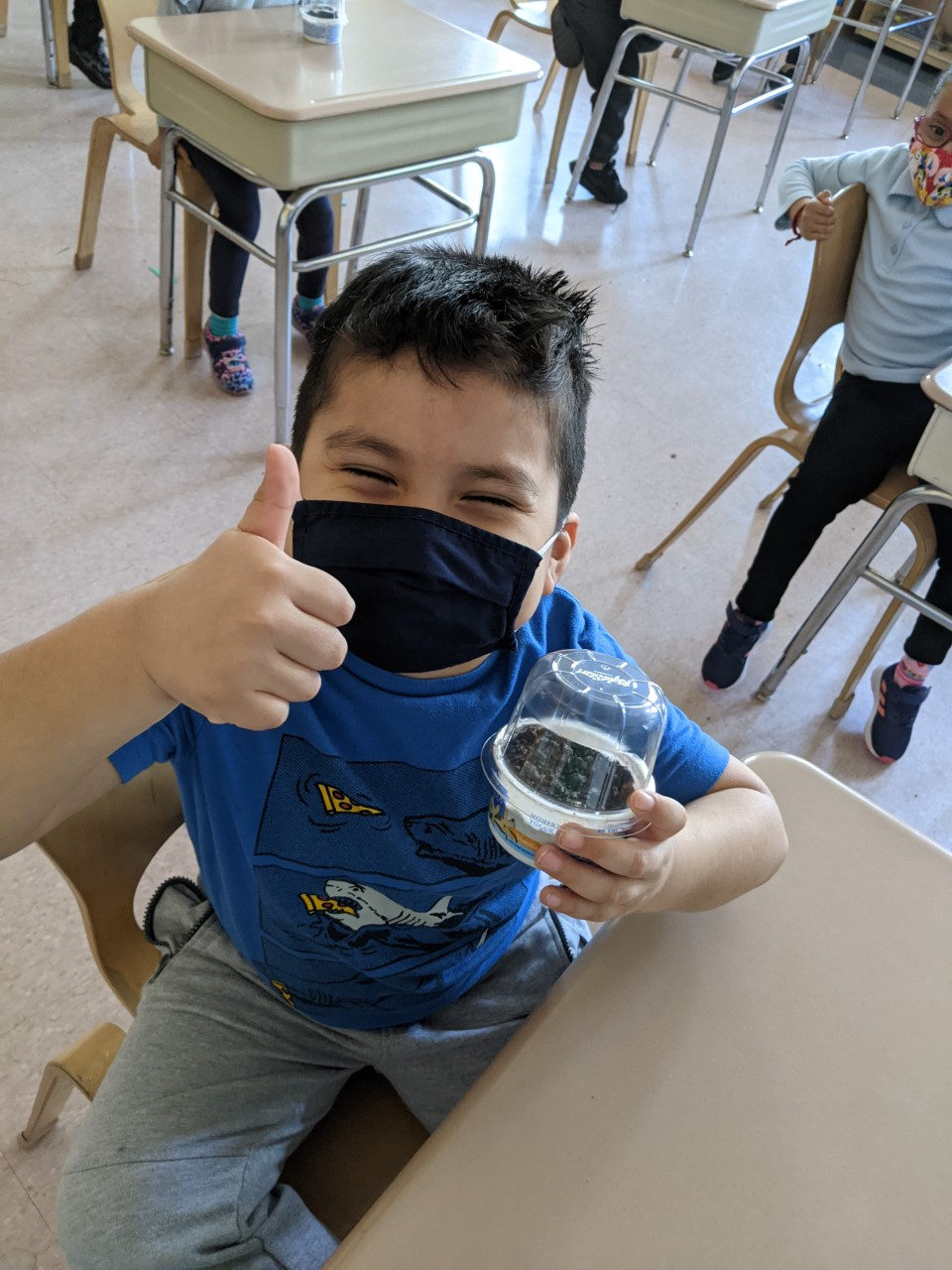 Student giving a thumbs up with his recycled-cup terrarium