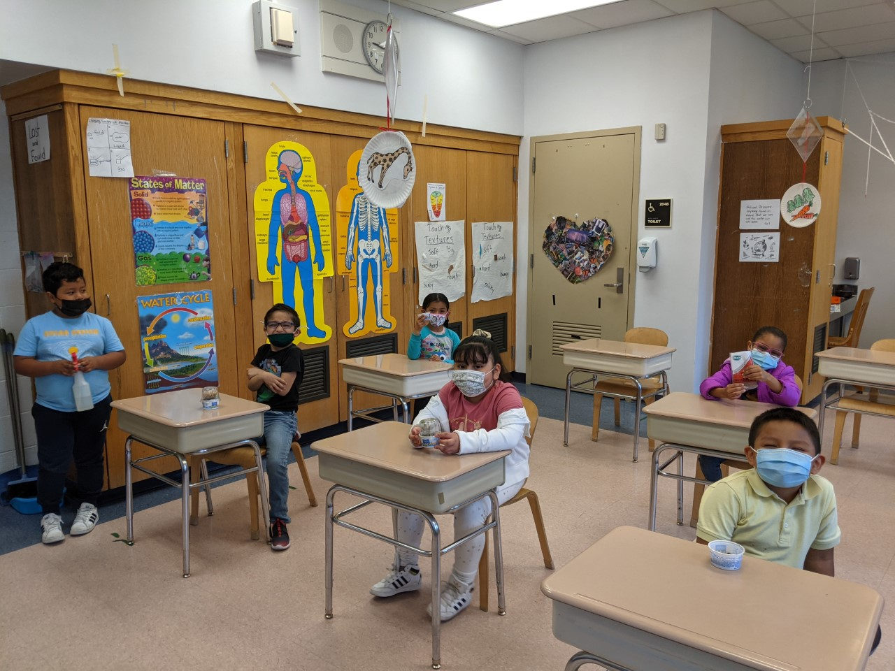 Students at spaced-out desks with their Earth Day projects