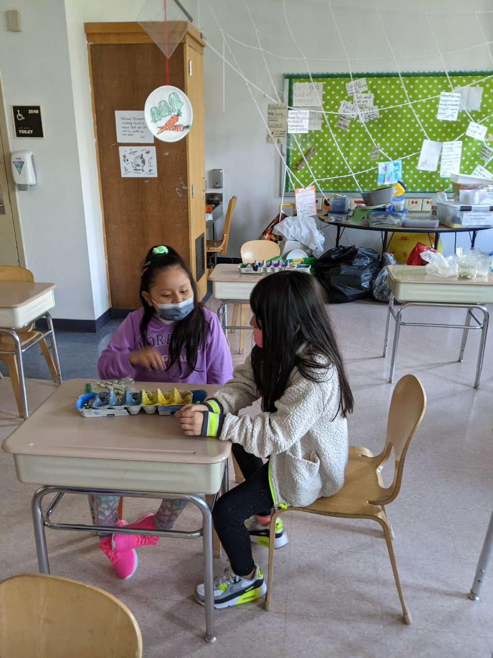 Students painting egg-carton Mancala boards at their desks