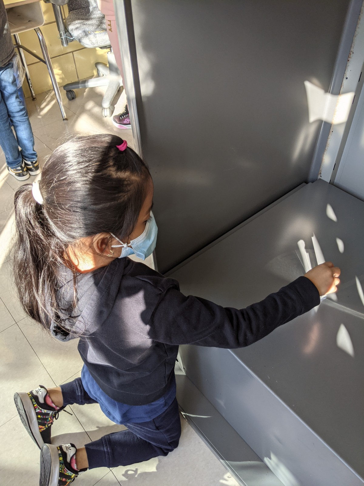 Student tracing light patterns on a metal cabinet