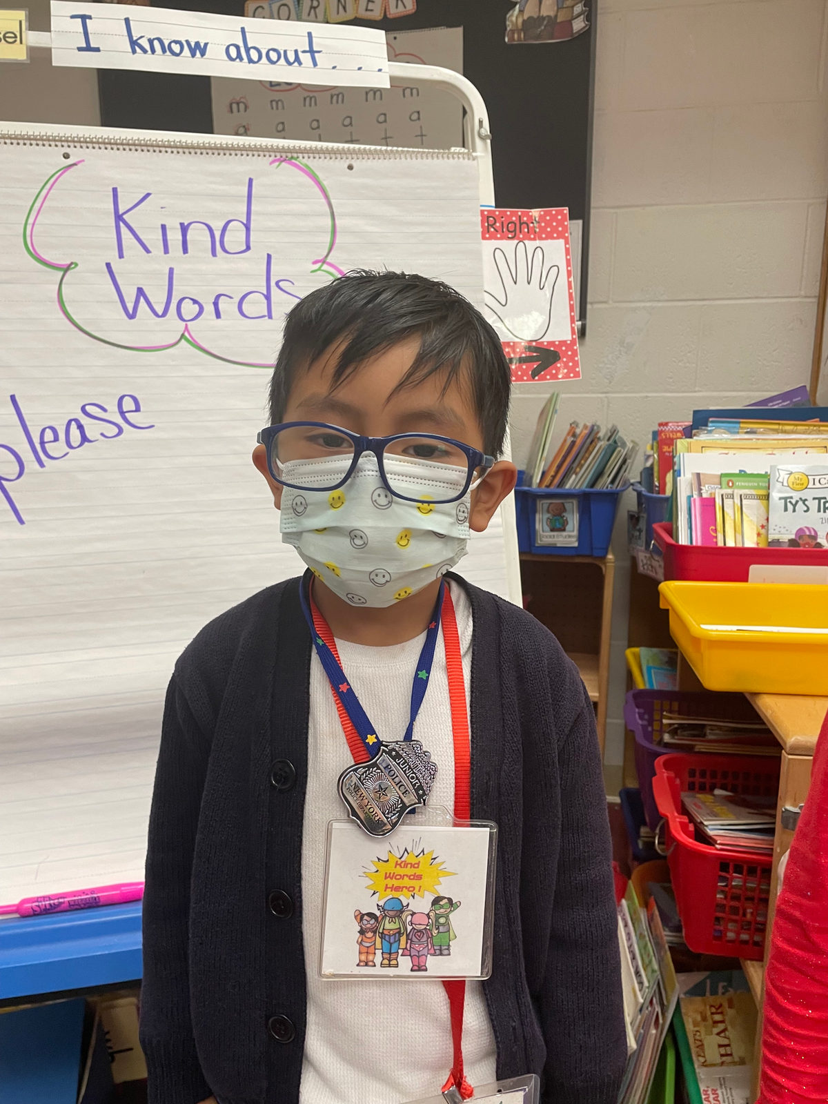 A student wearing a Kind Words Hero badge in front of a Kind Words chart