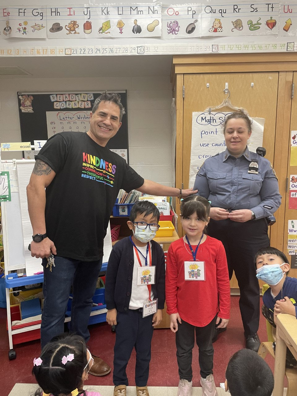 Principal Quintana and a police officer with students receiving Kind Words Hero badges in their classroom