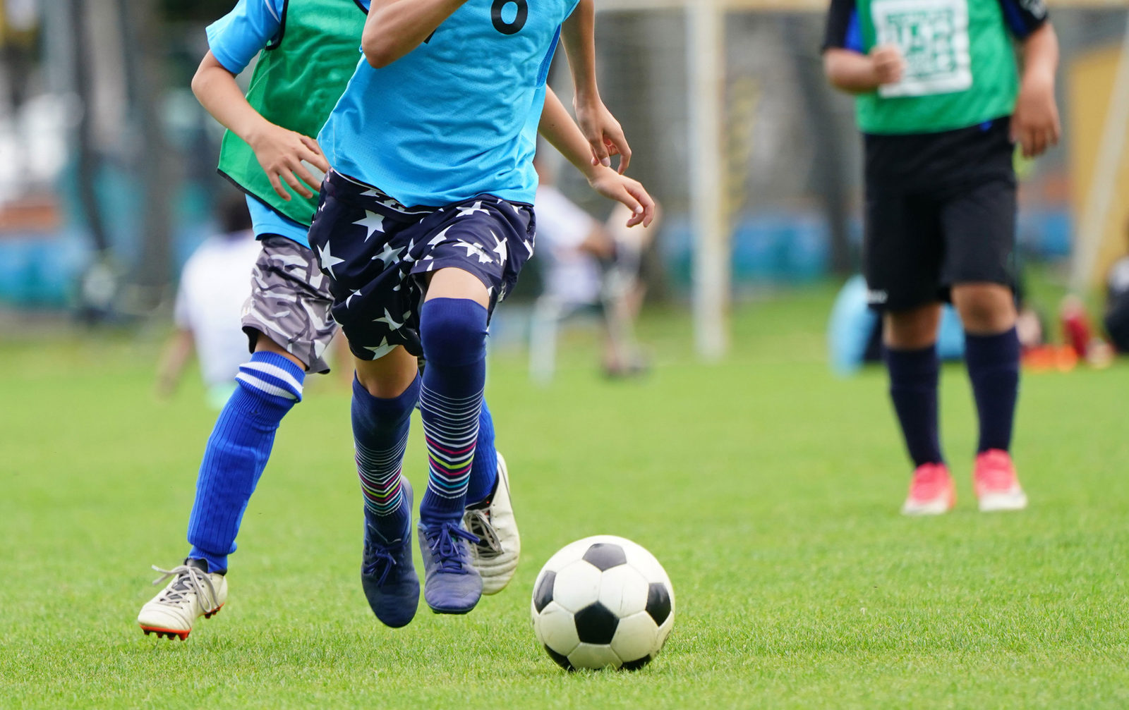 Children in team jerseys chasing a soccer ball on a grass field