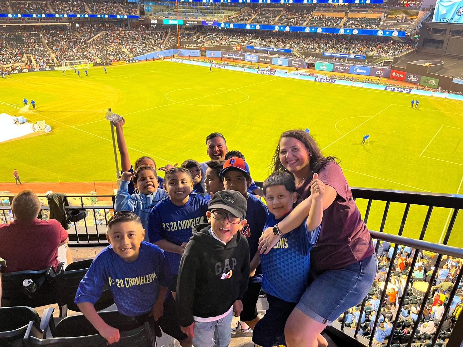 The Chameleons and coaches in the stands at a stadium soccer game
